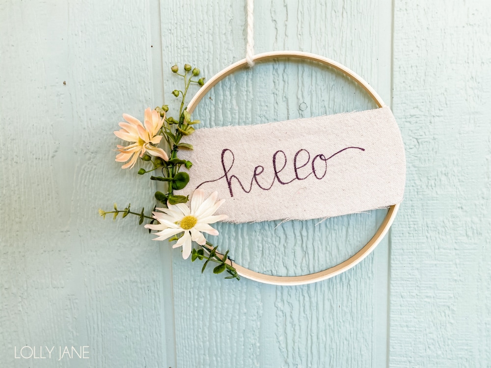 Simple Hoop Wreath with a hand written HELLO... so cute and EASY to make! #handmadewreath #diywreath #canvasbanner #diyhomedecor #homedecor #easytomakewreath